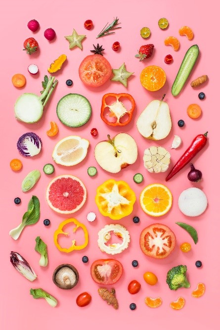 Pink backdrop with colorful fruits and vegetables displayed.